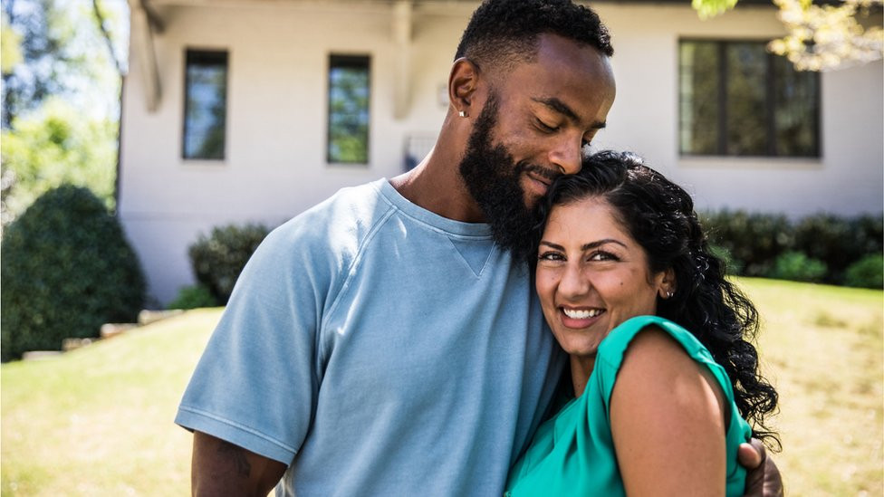 A couple hugging outside house