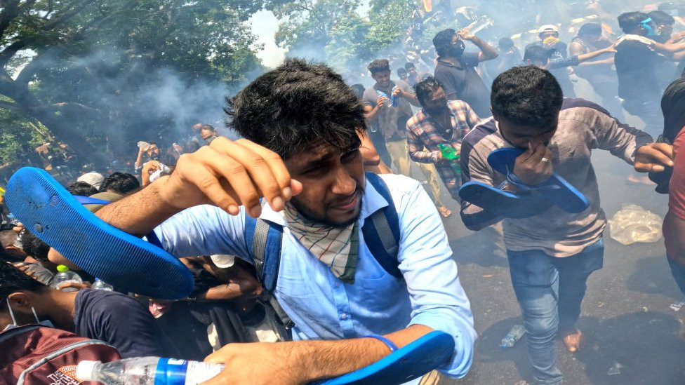 Sri Lankan anti-government protesters run away from tear gas during a protest that resulted in protesters occupying the prime