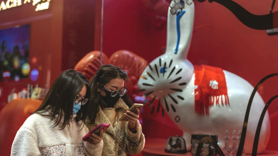 Two women wearing face masks in front of a pottery rabbit shop for the upcoming Chinese Lunar New Year in a supermarket in Beijing, China on 11 January 2023