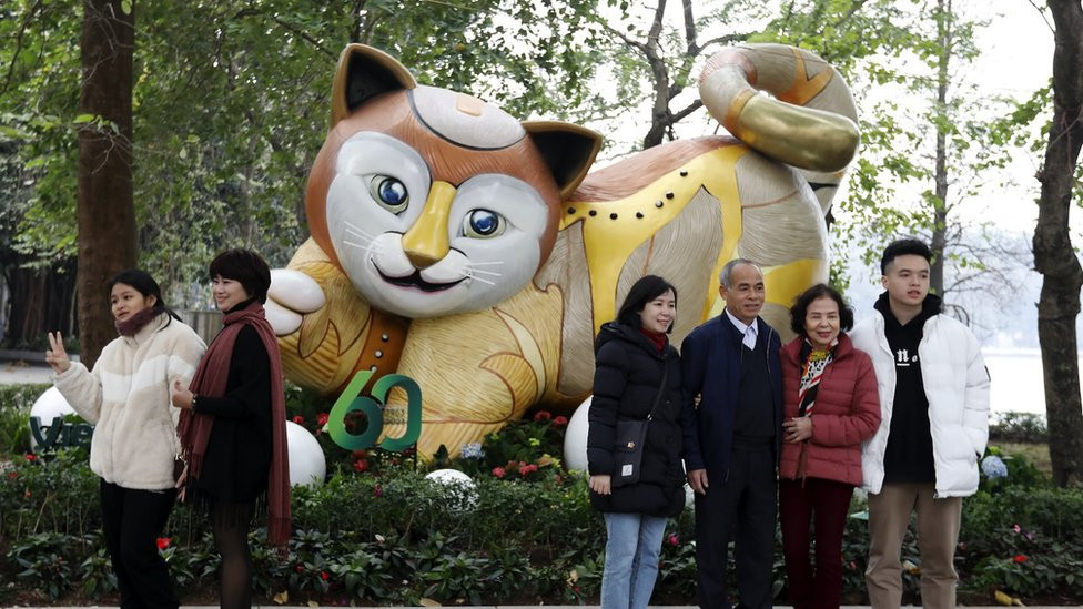 People pose in front of a giant cat in a Hanoi park