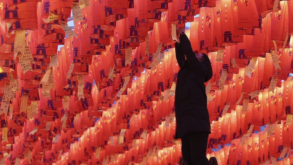 A visitor hangs a red paper lantern with New Year's wishes during a lantern show on the ancient city wall of Xian in China