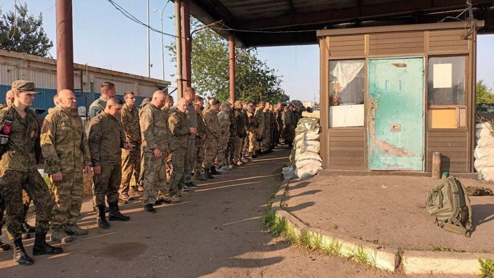 This photo released by Wagner Group says it shows Russian border guards at a checkpoint laying down their weapons