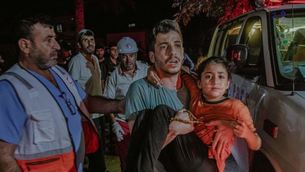 A man carries a girl, who appears to be nursing light injuries, in Gaza City