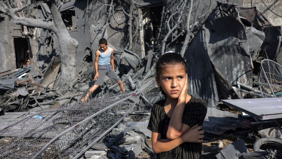 Two children stand in a devastated building in Gaza