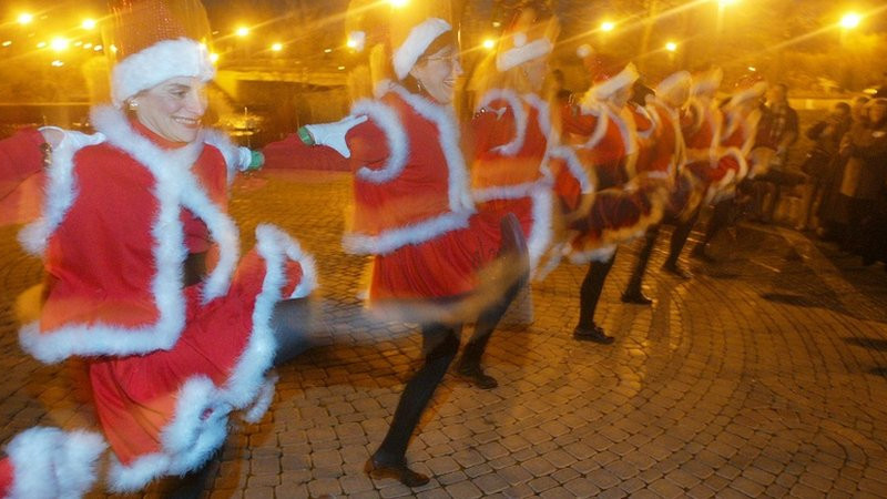 Family and friends of the community of Naperville, Naperville (Illinois, United States) celebrating the winter solstice dressed in Santa Clause outfits and dancing along the Riverwalk.