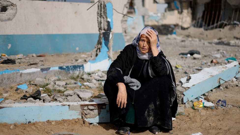 A woman sits next to a destroyed building in Rafah, southern Gaza. Photo: February 2024
