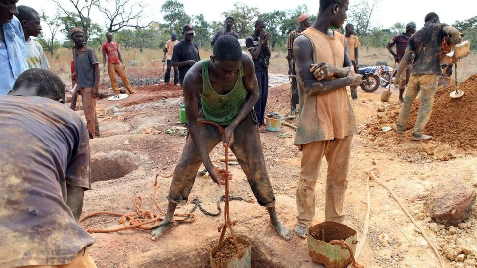 Gold miners empty containers of earth removed from a mining shaft in Koflatie, Mali, on October 28, 2014, a mine located a few miles from the border with its southwestern neighbour Guinea.