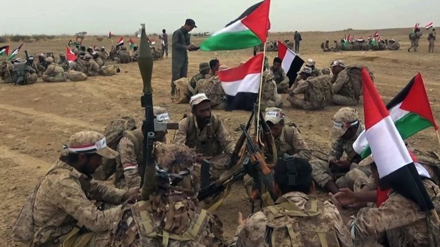 Houthi fighters sitting around a flag