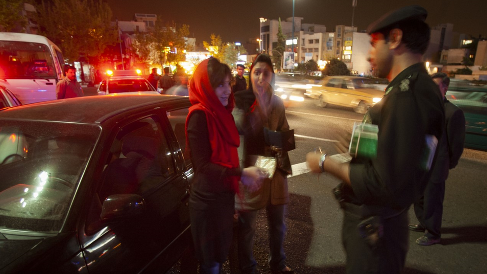 An officer with the morality police questions women in Iran