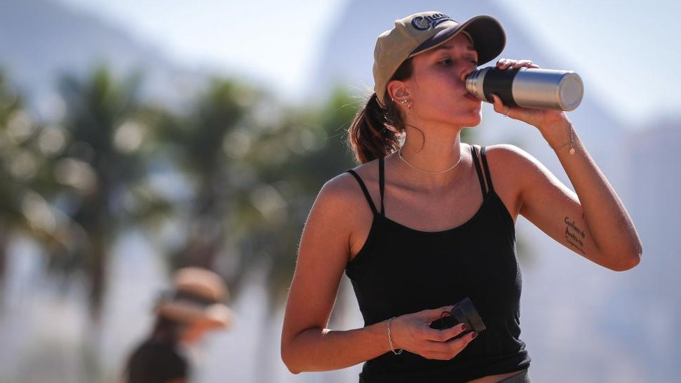 A woman drinks water on Copacabana Beach in Rio de Janeiro, Brazil, during a heatwave