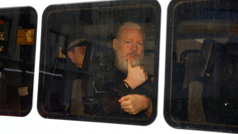 Assange gestures with a thumbs up after he was arrested by Met Police officers at Ecuador's embassy in London