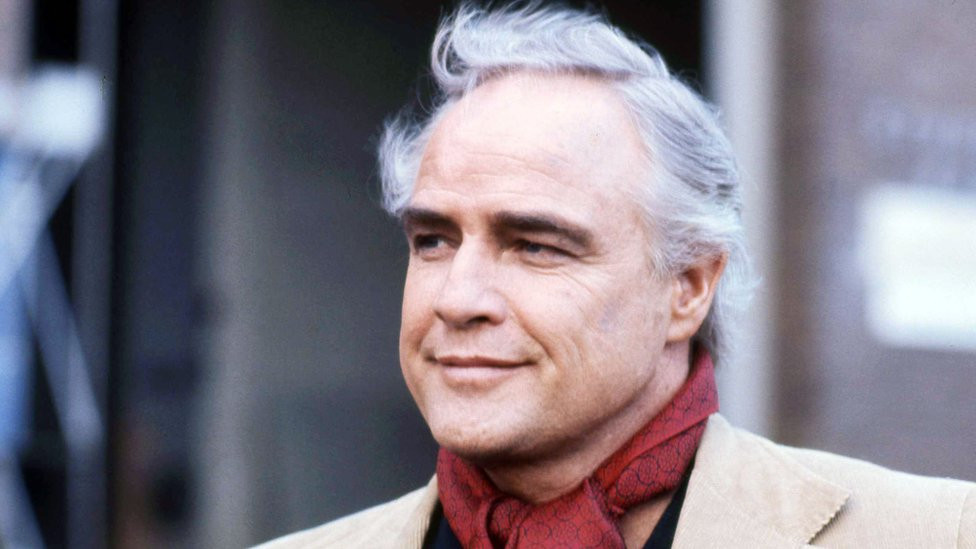 Glumac Marlon Brando u kaputu sa crvenim šalom