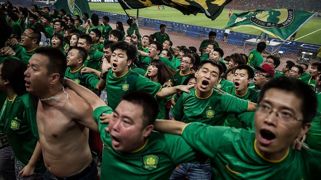 Beijing Guoan fans sing and jump with their backs to the pitch during a Chinese Super League game