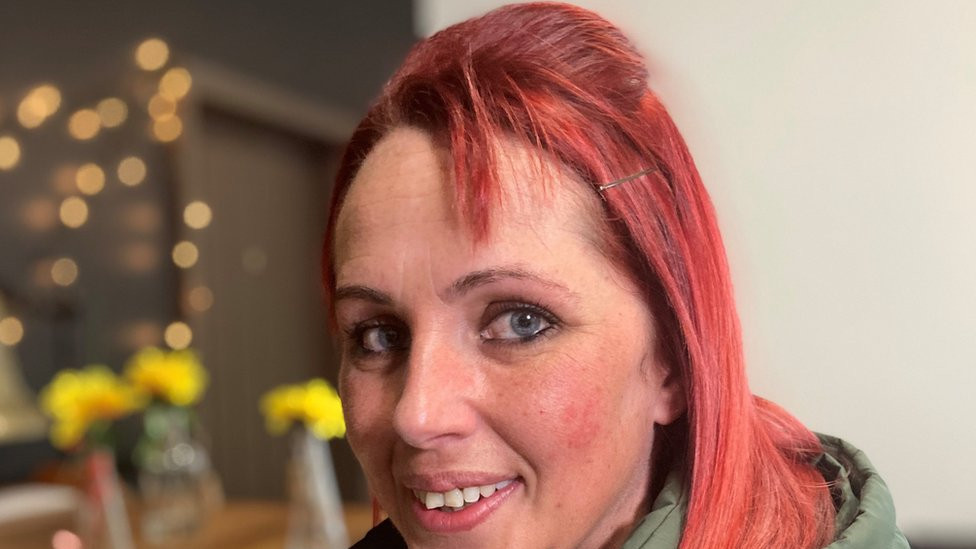 A young woman with red hair smiles at the camera