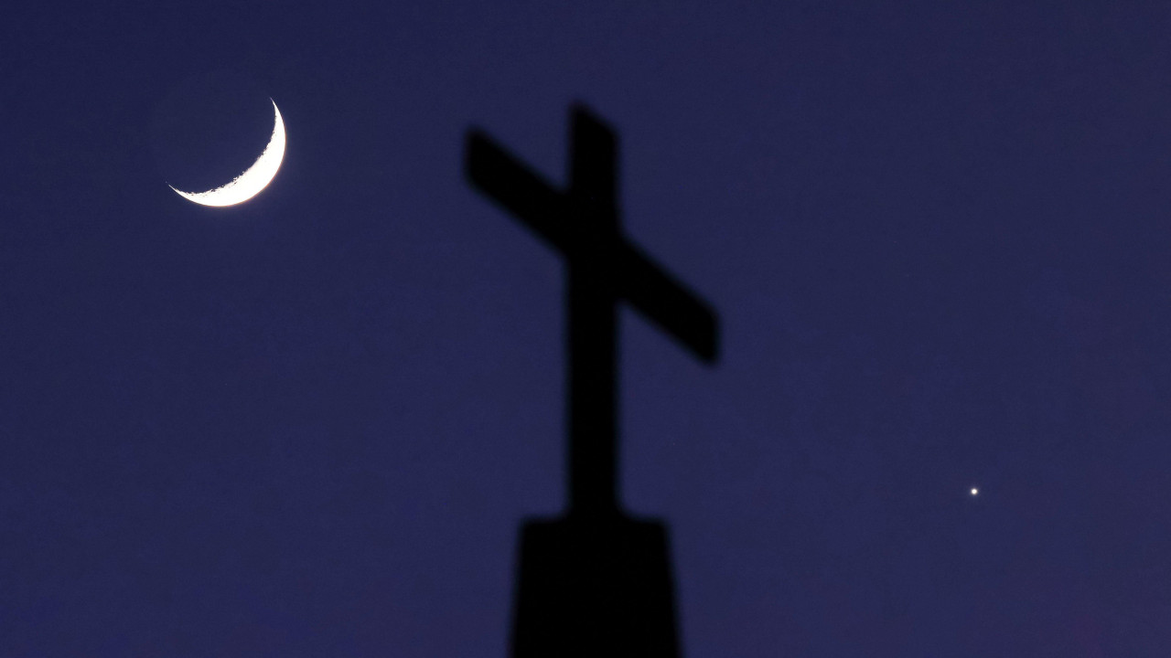 A crescent moon and the planet Venus straddle a cross on top of Quebec Baptist Church in Ellaville, Georgia