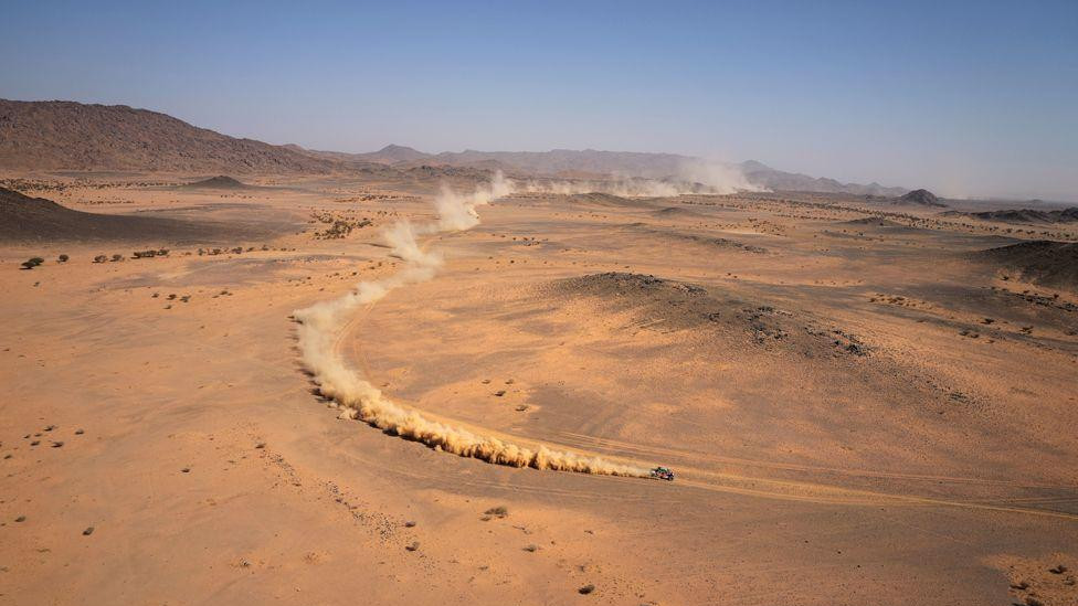 Oblak prašine iza kola u Saudijskoj pustinji tokom Dakar relija 