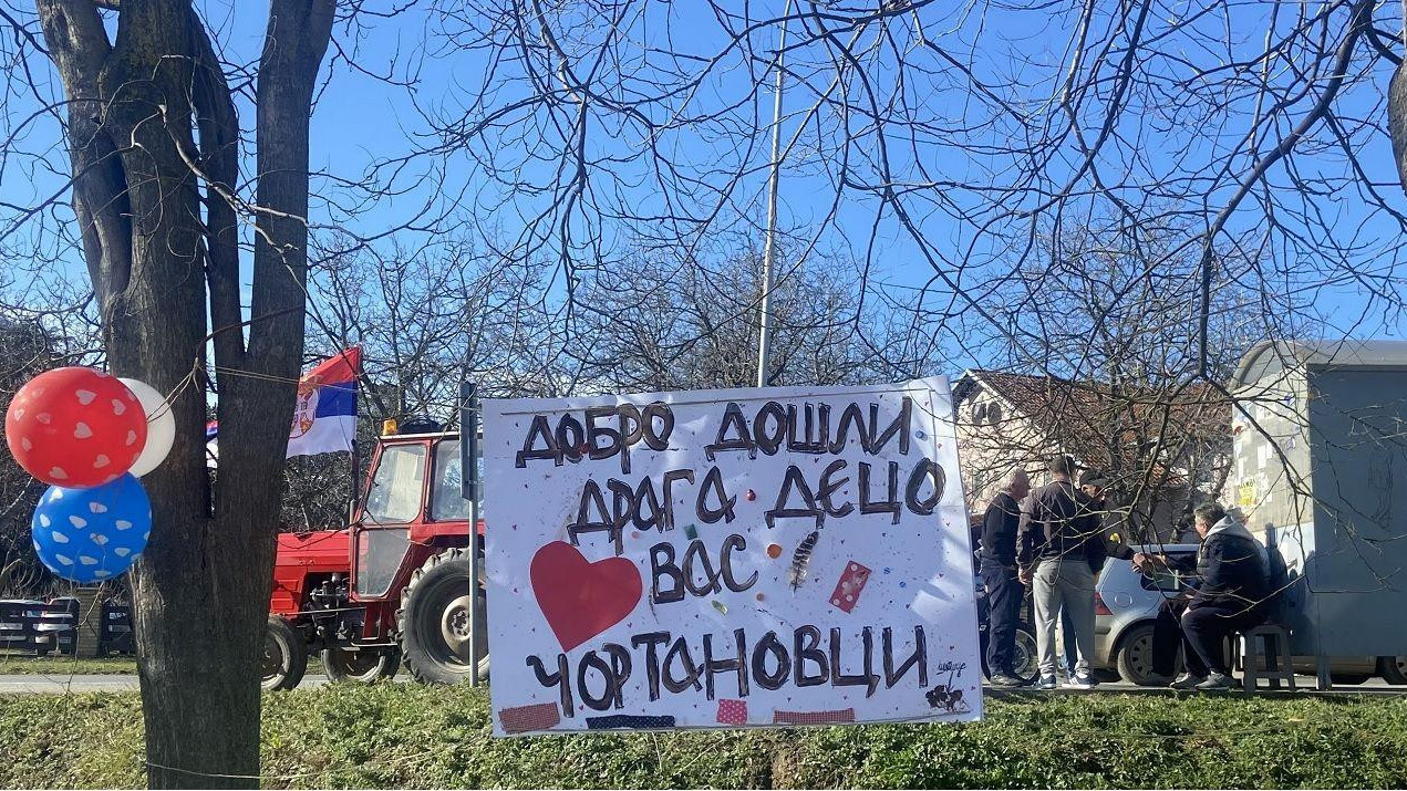 baloni, zastava Srbije i ljudi sa plakatom sede i čekaju studente