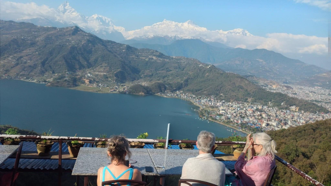 Troje turista sa visine posmatraju Himalaje, okrenuti leđima