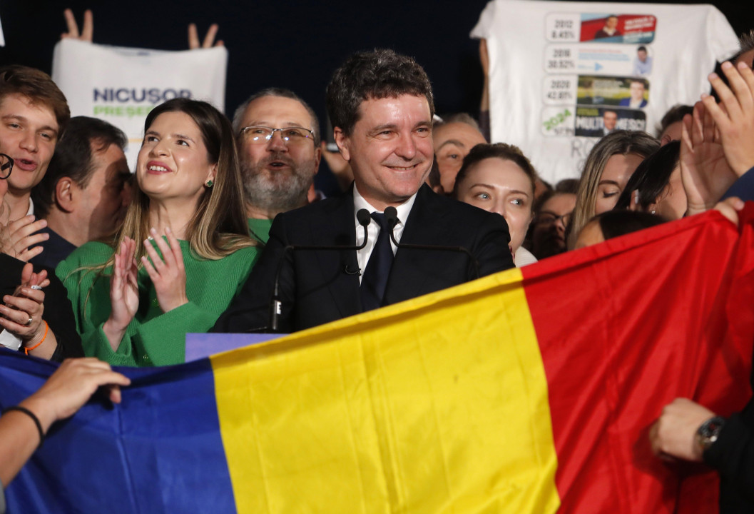 Muškarac drži zastavu i smeje se okružen ljudima