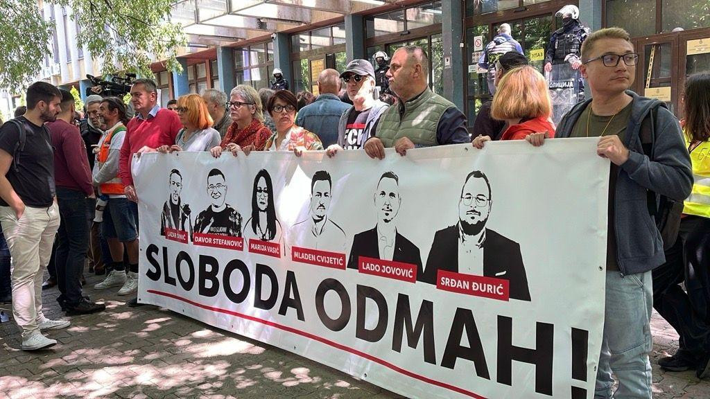Ispred glavnog ulaza, jednog od četiri blokarana, posebno se ističe transparent „Sloboda odmah" sa iscrtanim likovima pritvorenih.