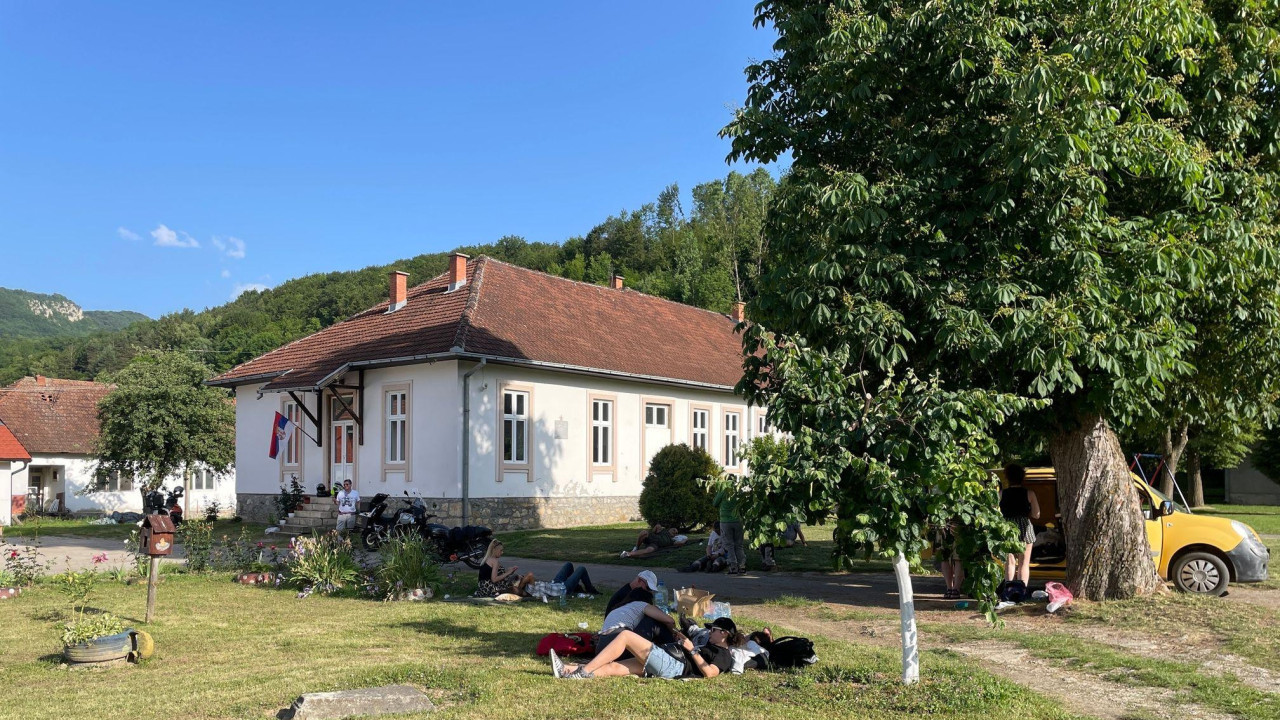 Ljudi leže na travnjaku u blizini kuće u kojoj se glasa