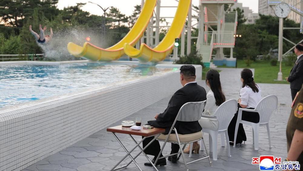 Severnokorejski lider Kim Džong Un, njegova ćerka Kim Džu Ae i supruga Ri Sol Džu posmatraju osobu koja se spušta niz žuti tobogan u vodenom parku u odmaralištu Vonsan Kalma, tokom ceremonije povodom završetka izgradnje odmarališta.