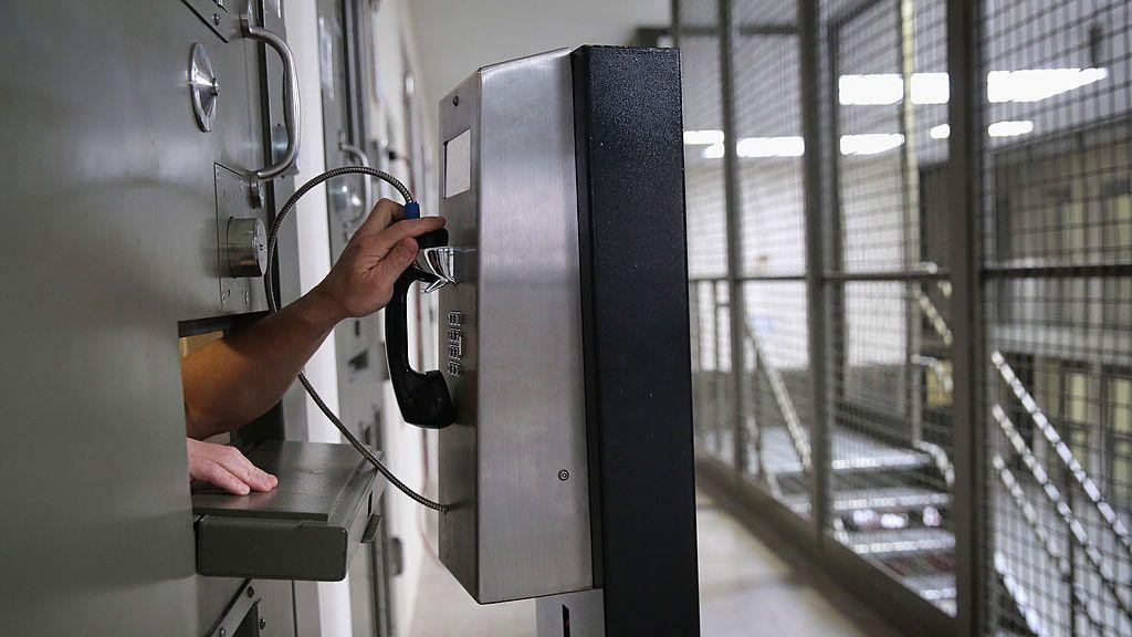 Ruka se pruža iz ćelije unutar imigrantskog pritvorskog centra Adelanto da bi dohvatila telefonsku govornicu. Ćelija ima samo mali otvor za ispruženu ruku.