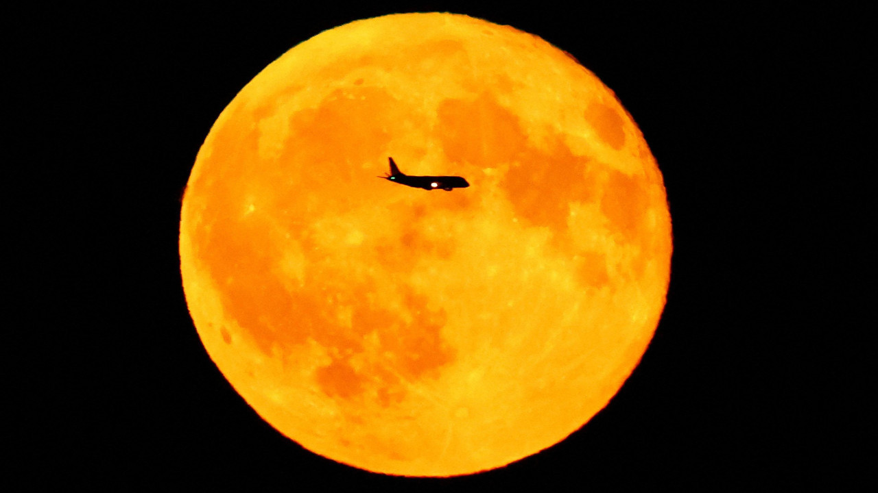 Putnički avion prolazi pored punog meseca iznad Frankfurta u Nemačkoj