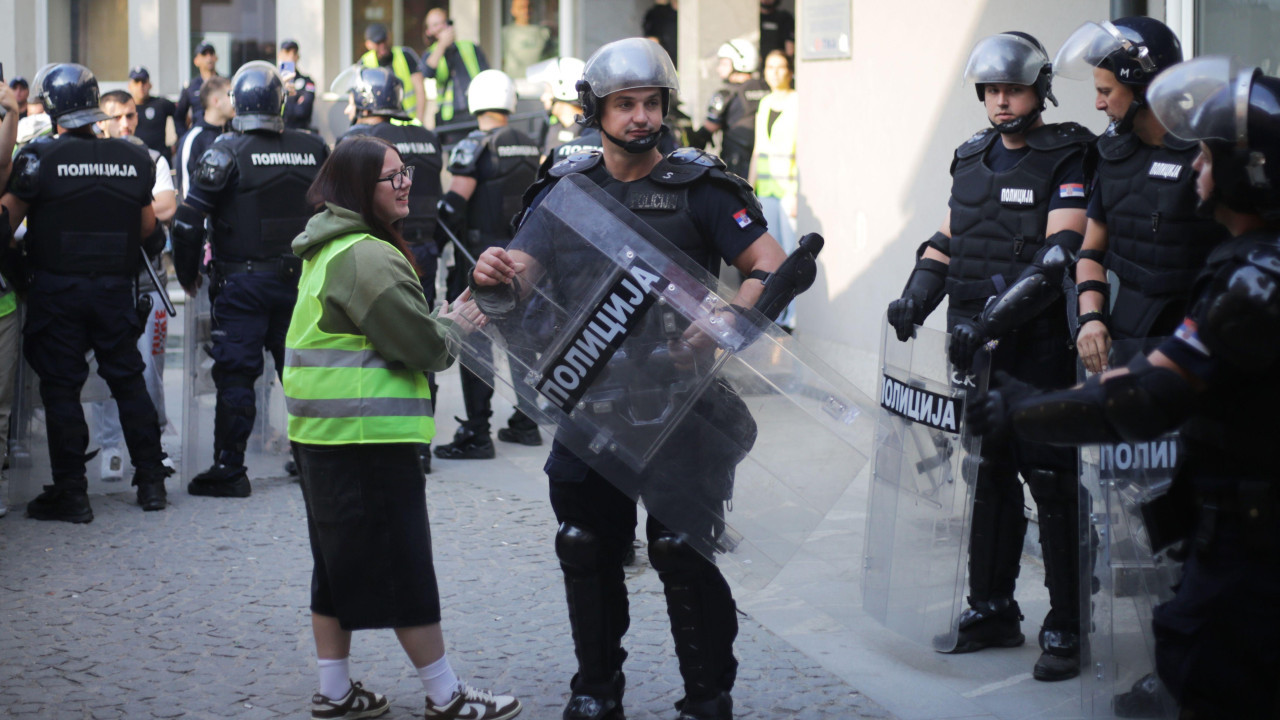 Studentkinja sa policajcem koji drži štit na ulici