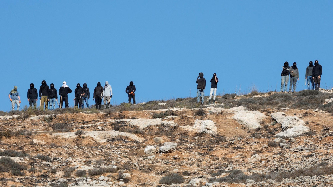 Izraelski doseljenici gledaju iz daljine kako izraelski vojnici ne dozvoljavaju palestinskim zemljoradnicima da beru masline blizu Ramale na Zapadnoj obali pod izraelskom okupacijom