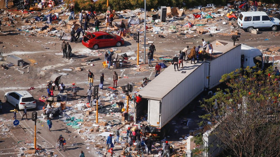 People loot an area near a burning warehouse