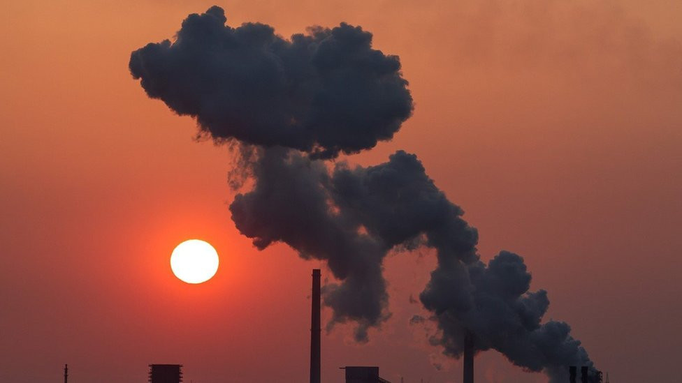 Smoke coming from industrial chimneys against a red sky